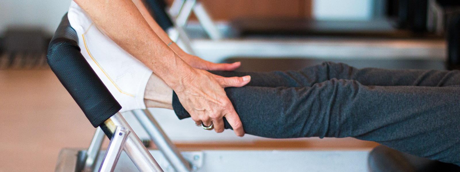 Pilates instructor in Lenexa KY is providing hands-on adjustments to  client during a private Pilates lesson on the reformer